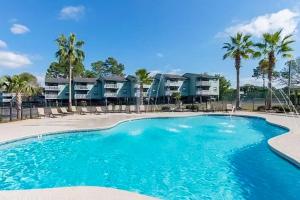 une piscine avec des chaises et des palmiers en face des condos dans l'établissement Bayview, à Orange Beach