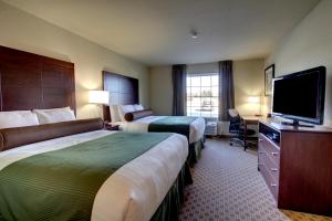 a hotel room with two beds and a flat screen tv at Cobblestone Inn & Suites - Rugby in Rugby