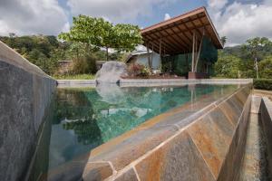 a pool of water with a house in the background at Eden Tica Lodge in Uvita