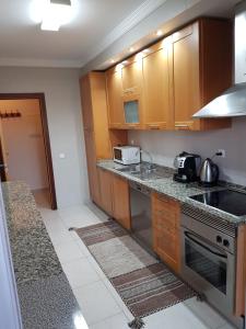 uma cozinha com armários de madeira e um forno com placa de fogão em Fantástico Apartament em Portimão