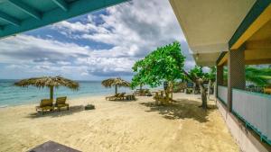 a beach with chairs and umbrellas and the ocean at Tamboo Resort in Negril