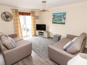 a living room with two couches and a tv at Sandy Bay House in Saundersfoot