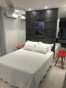 a bedroom with a large white bed with two red tables at Ipanema Prudente Studio in Rio de Janeiro