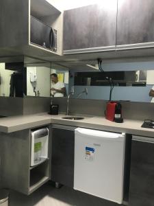a kitchen with a sink and a person in the mirror at Ipanema Prudente Studio in Rio de Janeiro
