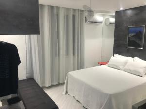 Ipanema Prudente Studio في ريو دي جانيرو: غرفة نوم بسرير أبيض ومروحة سقف