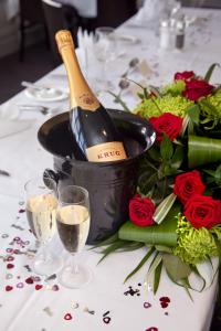 a bottle of wine in a bucket on a table with roses at Mercure London Staines-upon-Thames Hotel in Staines