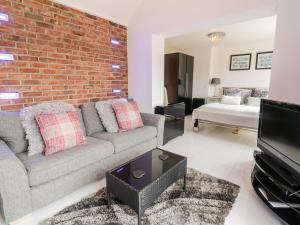 a living room with a couch and a brick wall at Smithy Cottage in Cemaes Bay