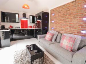 a living room with a couch and a brick wall at Smithy Cottage in Cemaes Bay