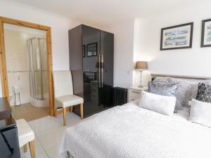a bedroom with a bed and a chair and a mirror at Smithy Cottage in Cemaes Bay
