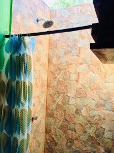 um chuveiro com uma porta de vidro ao lado de uma parede de pedra em Sunrise El Paredón em El Paredón Buena Vista