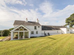una casa bianca con un ampio prato di Buarthau Cottage a Caernarfon