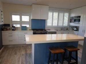 een keuken met witte kasten en een blauw eiland met krukken bij Waterfront Location - 2 Bed Apartment in Corlette, Port Stephens - Sleeps 4 in Corlette