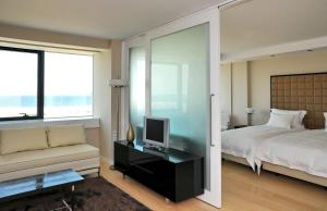 フィゲイラ・ダ・フォズにあるスウィート アトランティック ホテル & スパのベッドルーム(ベッド1台、テレビ、ソファ付)