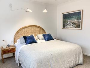 a bedroom with a large bed with blue pillows at Pavilions Collection in Airlie Beach