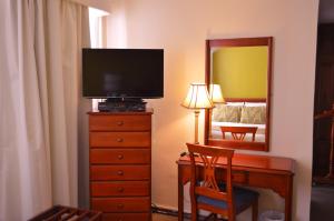 Schlafzimmer mit einem Schreibtisch, einem TV und einem Spiegel in der Unterkunft La Carolina Inn in Quito