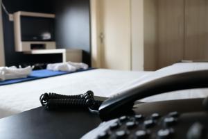 un teléfono sentado en un escritorio junto a una cama en Soratur Hotel & Coworking, en Criciúma