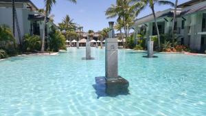 a pool of water with a sign in the middle at Temple Resort & Spa Port Douglas in Port Douglas