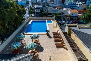 a swimming pool with chairs and umbrellas on a building at A Furninha Hotel in Torres