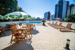 una fila de sillas y mesas con sombrilla junto a una piscina en A Furninha Hotel, en Torres