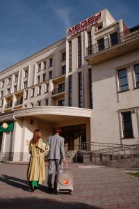 un homme et une femme marchant devant un hôtel dans l'établissement Medeu, à Kostanay