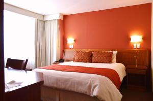 キトにあるLa Carolina Innの赤い壁の大型ベッドが備わるホテルルームです。