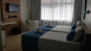 a hotel room with two beds and a television at Flats a beira mar em hotel na pajuçara in Maceió