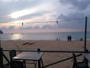 a table and chairs on a beach with the ocean at Rainbow Tioman Cottage in Kampong Juara