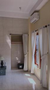 a room with white curtains and a window at Tasik Dumun Homestay and Waroeng in Amed