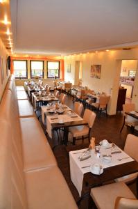 Hotel Pirsch في رامشتاين-ميزنباخ: غرفة طعام مع طاولات وكراسي في مطعم