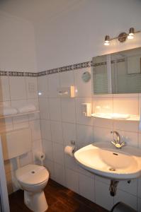 a white bathroom with a toilet and a sink at Hotel Pirsch in Ramstein-Miesenbach