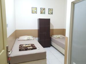 a small room with two beds and a cabinet at Delta Inn Bogor Syariah for Indonesian Only in Bogor