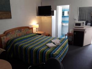 a bedroom with a bed with a colorful blanket on it at Snowdream Motel in Berridale