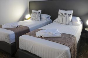 Dos camas en una habitación de hotel con toallas blancas. en Re Vittorio De Luxe, en Messina