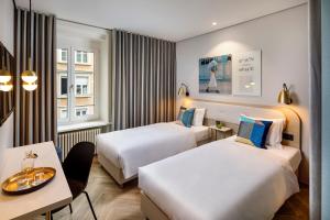 ein Hotelzimmer mit zwei Betten und einem Tisch in der Unterkunft Hotel Felix in Zürich
