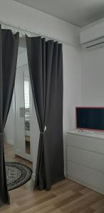 Habitación con cortina negra y TV. en Butas Vytauto 7-4, en Rokiškis