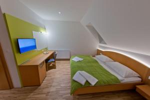 a bedroom with a bed with a desk and a monitor at Hotel Restaurant Meyer in Kalsdorf bei Graz