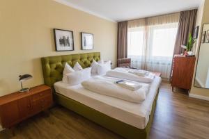 a bedroom with a large bed with a green headboard at Luis City Apartments Regensburg in Regensburg