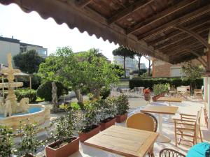 un patio con tavoli, sedie e fontana di Hotel Villa Colombo a Lido di Camaiore