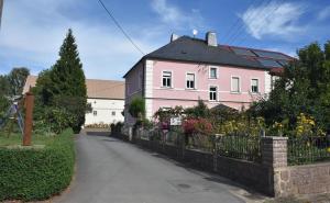 a pink house with a fence and flowers at Ferienhof Schwäbe in Lommatzsch
