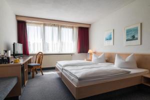 GrötzingenにあるHotel Aichtaler Hofのベッドとデスクが備わるホテルルームです。
