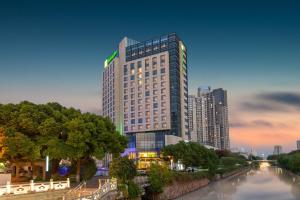Un edificio alto vicino a un fiume in una città di Holiday Inn Taicang City Centre, an IHG Hotel a Taicang