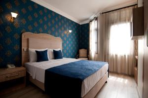 a bedroom with a bed with blue walls and a window at Artefes Hotel Old City in Istanbul