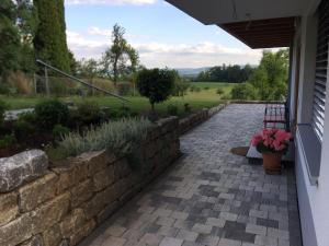 a patio with a stone retaining wall and flowers at Ferienwohnung Kiesel in Krapfenreut