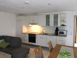 a kitchen with white cabinets and a couch and a table at Ferienwohnung Kiesel in Krapfenreut