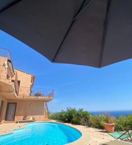 a swimming pool in front of a house with the ocean at Villa Pétale de Rose in Cavalaire-sur-Mer