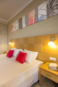 a bedroom with a white bed with red pillows at Hotel Cooee Albatros in Moraitika
