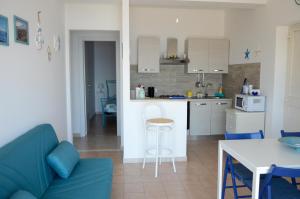 a living room with a blue couch and a kitchen at Residenza Jonica in Letojanni