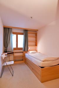 a bedroom with a bed and a desk and a window at Chesa Fuolla Rosa - Celerina in Celerina