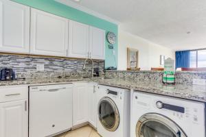 une cuisine avec des armoires blanches et une laveuse et une sécheuse dans l'établissement Palms Resort 1502, à Myrtle Beach