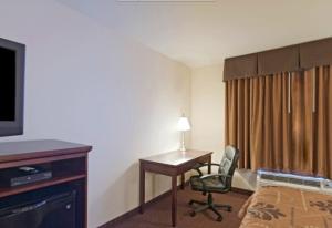 ein Hotelzimmer mit einem Schreibtisch, einem Bett und einem TV in der Unterkunft Americas Best Value Inn Saint Robert/Fort Leonard Wood in Saint Robert